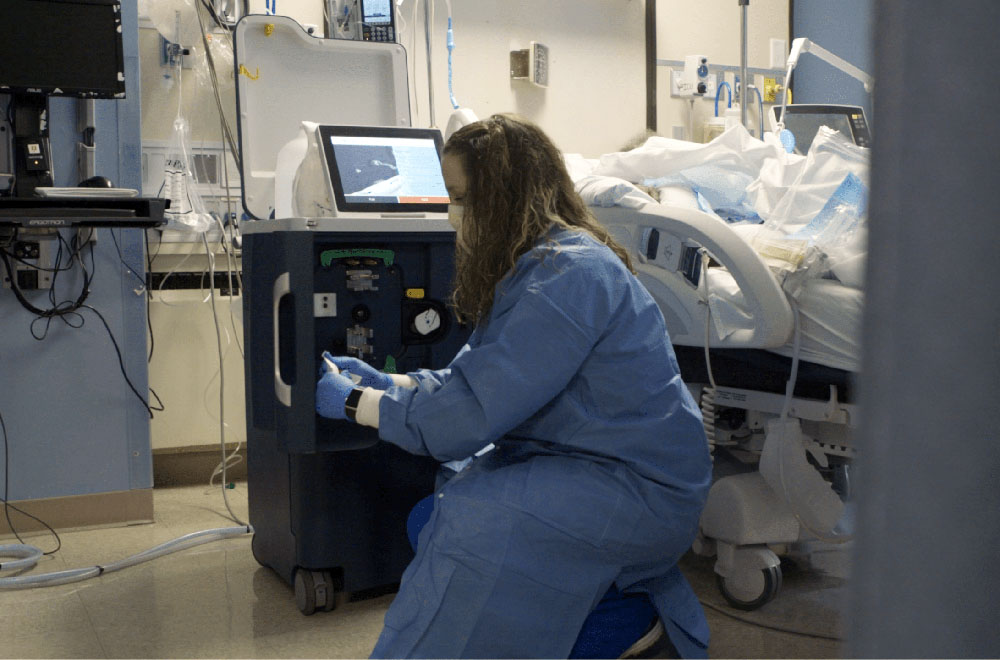 Nurse-with-tablo-icu- Nurse kneeling next to Tablo dialyzing in an ICU