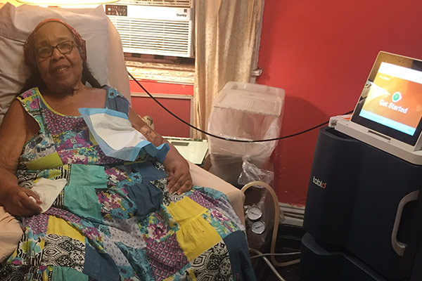 Woman sitting in a chair preparing for treatment on her Tablo Hemodialysis System.