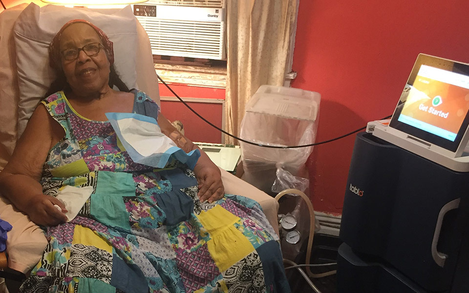 Woman sitting in a chair preparing for treatment on her Tablo Hemodialysis System.