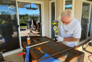 Man working outdoors with a power tool on a woodworking project