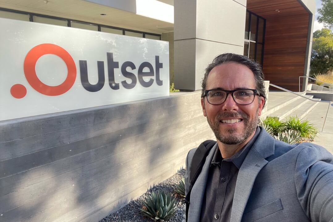 Selfie of employee by the Outset building sign