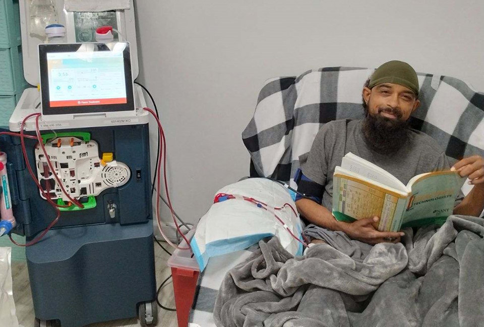 Man sitting in a chair with a book during Tablo home dialysis treatment.