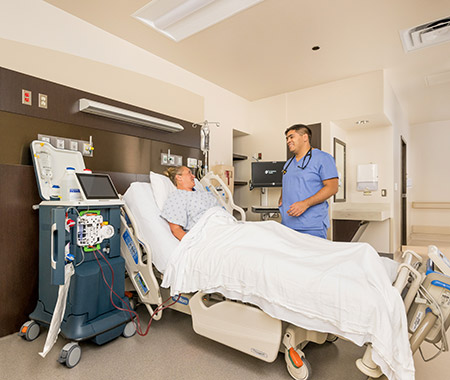 a man standing next to a man in a hospital bed