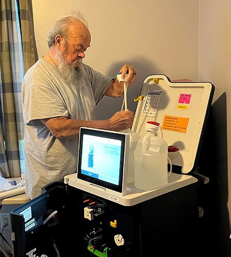 Man setting up his Tablo Hemodialysis System at home before starting treatment.