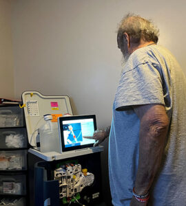 Man interacting with a Tablo Hemodialysis System touchscreen at home before starting treatment.